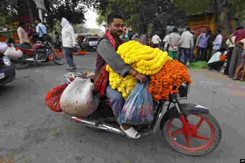 Seorang pria membawa karangan bunga marigold di atas sepeda motornya selama festival Diwali di Allahabad, India. (AP/Rajesh Kumar Singh)