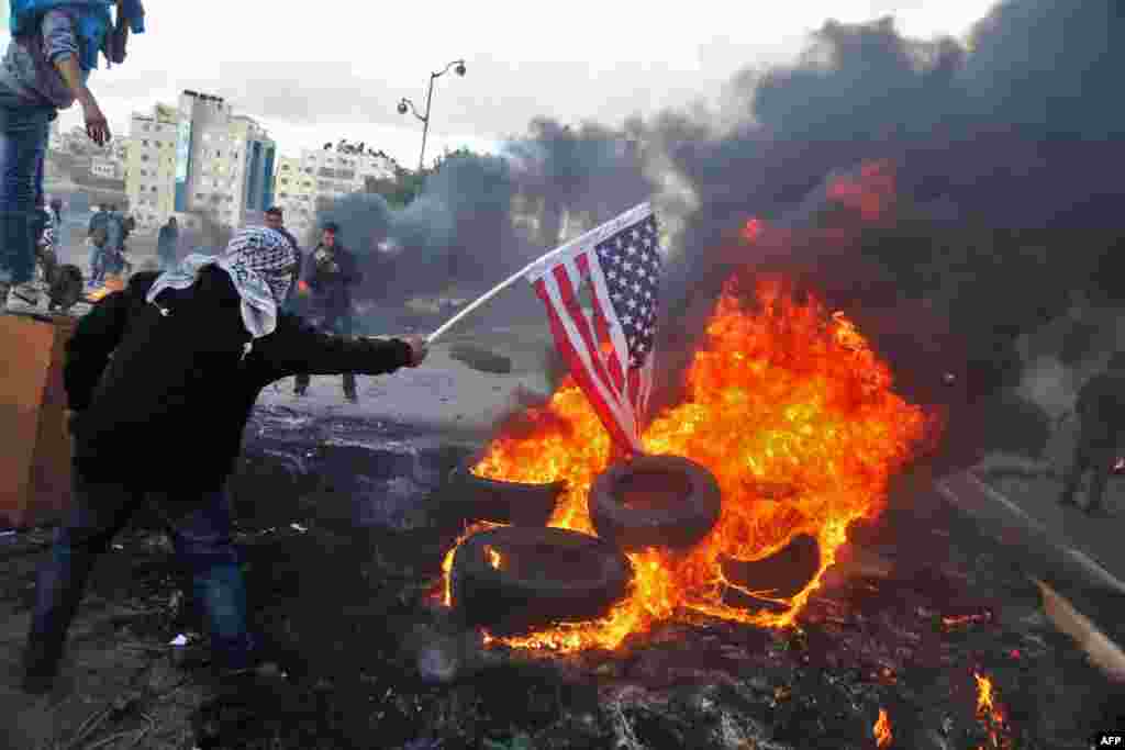 Seorang demonstran Palestina&nbsp;membakar bendera Amerika dalam aksi protes di Tepi Barat, menentang keputusan Presiden Donald Trump mengakui Yerusalem sebagai ibu kota Israel.