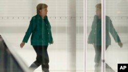 FILE - German Chancellor Angela Merkel walks through a corridor of the Reichstag building during a Christian Union parties faction meeting in Berlin, Sept. 25, 2018.