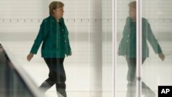 FILE - German Chancellor Angela Merkel walks through a corridor of the Reichstag building during a Christian Union parties faction meeting in Berlin, Sept. 25, 2018.