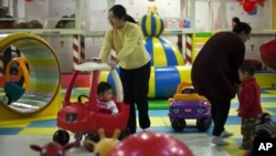 Para ibu dan anak-anak mereka di arena permainan dalam mal di Beijing. (Foto: Dok)