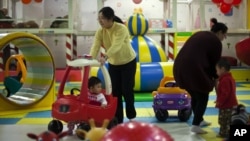 Parents play with their children at a kid's play area in a shopping mall in Beijing. Authors of a new study say the one-child policy has significant ramifications for Chinese society, January 10, 2013.