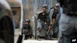 Policías afganos se protegen del fuego talibán luego de un ataque suicida en Kabul, la capital de Afganistán.