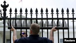 FILE - U.S. government contractors begin the installation of additional security spikes on the existing White House perimeter fence in Washington, July 1, 2015.