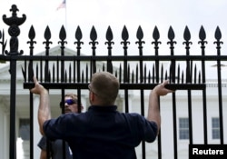 FILE - U.S. government contractors begin the installation of additional security spikes on the existing White House perimeter fence in Washington, July 1, 2015.