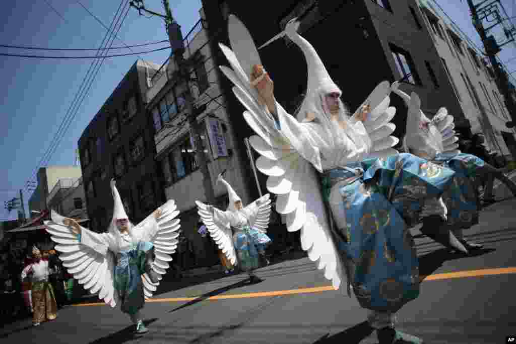 Para penari dengan menggunakan kerudung ala burung Heron menari sambil berparade di jalan-jalan menuju Kuil Asakusa di kompleks Kuil Sensoji di Tokyo, Jepan, sebelum Festival Tahunan Sanja, salah satu dari tiga festival penting yang dijadwalkan pada&nbsp; 16-18 Mei.
