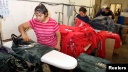 Workers press women's t-shirts after they have been printed with designs at the Sledge USA clothing factory in Los Angeles, California, Oct. 13, 2009. 