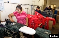 Workers press women's t-shirts after they have been printed with designs at the Sledge USA clothing factory in Los Angeles, California, Oct. 13, 2009.