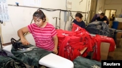Trabajadores presionan las camisetas de mujeres después de haber sido impresas con diseños en la fábrica de ropa, Sledge USA, en Los Ángeles, California.