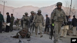 U.S. soldiers walk past the scattered parts of a vehicle used in an explosion on the outskirts of Kabul, Afghanistan, 12 Nov. 2010.
