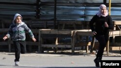 Children run fearing sniper fire in the northern Lebanese city of Tripoli, Jan. 20, 2014.