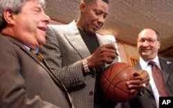 Brooklyn Bourough President Marty Markowitz, left, and CEO of Forest City Ratner Companies Bruce Ratner, right, pose with basketball legend Connie Hawkins as he autographs a basketball during a press conference in New York, Oct.14, 2003.