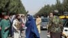 Pasukan Taliban memblokir jalan di sekitar bandara sementara seorang perempuan melintas, di Kabul, Afghanistan, Jumat, 27 Agustus 2021. (Foto: Reuters)