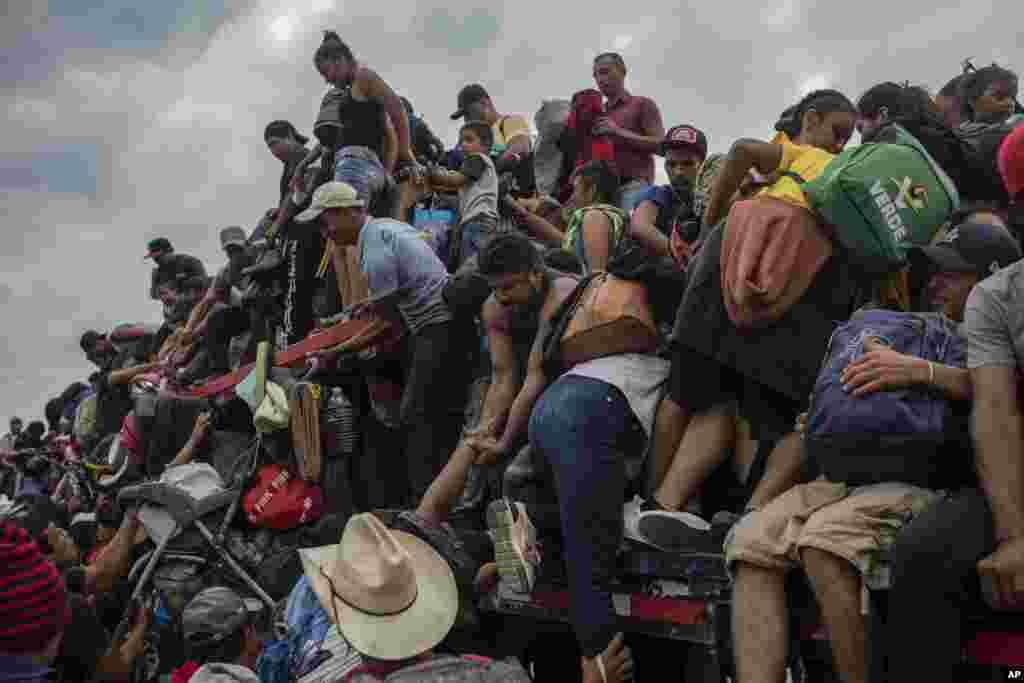 Migrants help fellow migrants onto the bed of a trailer in Jesus Carranza, in the Mexican state of Veracruz, Nov. 17, 2021. A group of mainly Central American migrants are attempting to reach the U.S.-Mexico border.