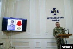 FILE - A photo of the director of the Kyiv office of Russian state news agency RIA Novosti, Kirill Vyshinsky, is seen on a monitor during a news briefing at the headquarters of the Ukraine's State Security Service (SBU) in Kyiv, Ukraine, May 15, 2018.