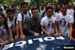 Myanmar journalists stand in front of a police vehicle transporting Reuters journalists Wa Lone and Kyaw Soe Oo to Insein prison after the court verdict in Yangon, Myanmar, Sept. 3, 2018.