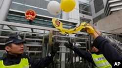 Police officers try to stop an anti-Beijing protester throwing a balloon with picture of jailed Chinese human rights activist Liu Xiaobo during a rally outside the Chinese liaison office in Hong Kong Thursday, Dec. 25, 2014.