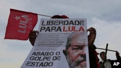 FILE - A supporter of Brazil's former president Luiz Inacio Lula da Silva holds a poster that reads in Portuguese: "Freedom for Lula," in Brasilia, Brazil, April 17, 2018.