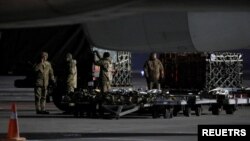 Miembros de los servicios ucranianos descargan un envío de ayuda militar entregada como parte de la asistencia de seguridad de EE. UU. a Ucrania, en el Aeropuerto Internacional de Boryspil en las afueras de Kiev, Ucrania, el 25 de enero de 2022. 