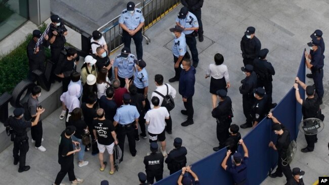 Investors are surrounded by police and security personnel as they try to enter the headquarters of the real estate developer Evergrande Group, Sept. 23, 2021, in Shenzhen, China.