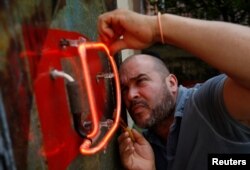 Cuban artist Kadir Lopez Nieves, who is restoring the vintage neon signs of the city, works in his workshop and gallery, in Havana, Cuba, Feb. 19, 2018.