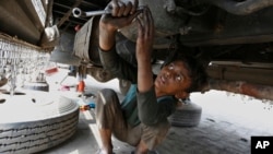 FILE - A 10-year-old boy works at an automotive repair shop in Lahore, Pakistan, to earn living for his family, June 12, 2021.