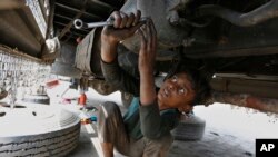 FILE - A 10-year-old boy works at an automotive repair shop in Lahore, Pakistan, to earn living for his family, June 12, 2021.