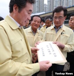 이낙연(왼쪽) 국무총리가 지난17일 호우 피해를 입은 충북 청주시 청주폐수처리장을 방문, 이시종(오른쪽) 충북도지사 등으로부터 특별재난지역 선포 촉구 성명서를 받고 있다.