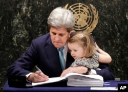 FILE - U.S. Secretary of State John Kerry holds his granddaughter Isabel Dobbs-Higginson as he signs the Paris Agreement on climate change, April 22, 2016, at U.N. headquarters.