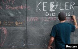 FILE - Russ Naranjo of Charlottesville writes a message about "Unite the Right" rally organizer Jason Kessler and the rally on the city's "Free Speech Wall" along the downtown mall in Charlottesville, Virginia, Aug. 14, 2017.