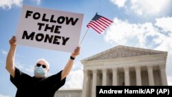 Bill Christeson holds up a sign that reads "Follow the Money" outside the Supreme Court, Thursday, July 9, 2020, in Washington. The court ruled that the Manhattan district attorney can obtain Trump's financial records. (AP Photo/Andrew Harnik)