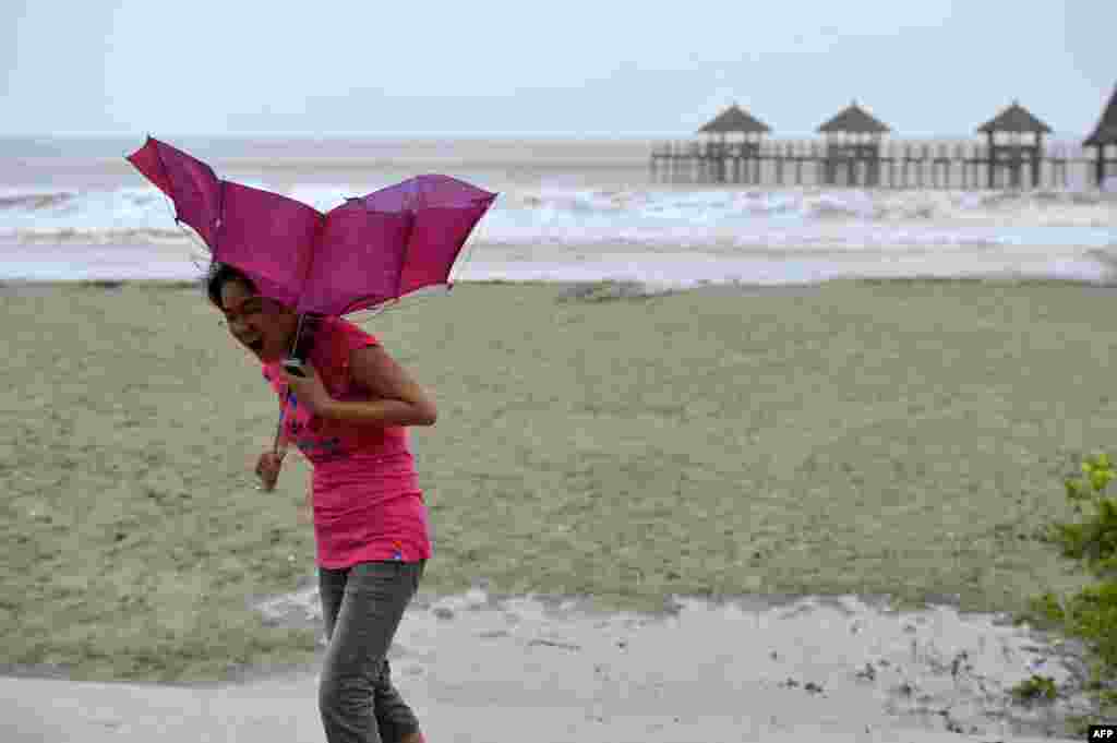 A woman walks on the beach of Qinglan port, as strong wind breaks her umbrella in Wenchang, south China's Hainan province. China braced for a powerful super typhoon heading for its southern coast after the storm left a trail of destruction and at least 40 dead in the neighboring Philippines.