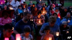 People bow their heads in prayer during a vigil Saturday, Oct. 3, 2015, in Winston, Oregon.