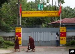 Buddhist monks walk past the front gate of Myanmar's opposition leader Aung San Suu Kyi's home in Yangon, Myanmar, Nov. 10, 2015.