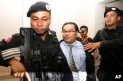 Opposition senator Hong Sok Hour, center, is escorted by riot police officers at Phnom Penh Municipal Court, in Phnom Penh, Cambodia, Saturday, Aug. 15, 2015.