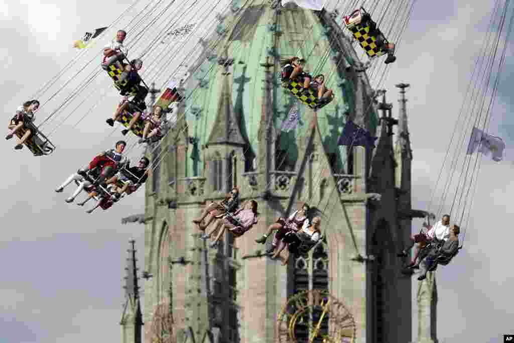 People ride a swing in front of St. Paul's church at the 183rd Oktoberfest beer festival in Munich, Germany.
