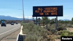 A road sign tells out-of-state visitors to quarantine for 14 days, or the duration of their stay if shorter, under an order by Governor Michelle Lujan Grisham, amid the coronavirus disease outbreak, in Pojoaque, New Mexico, U.S., July 9, 2020. (REUTERS/Andrew Hay)