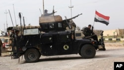 FILE - Iraqi security forces prepare to attack Islamic State extremists at Camp Speicher, the front line in Tikrit, 80 miles (130 kilometers) north of Baghdad, March 12, 2015. 