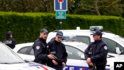 French police officers block the road leading to a crime scene the day after a knife-wielding attacker stabbed a senior police officer to death Monday evening outside his home in Magnanville, west of Paris, June 14, 2016. 