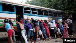 Para pengunjuk rasa menggunakan bus yang terbakar sebagai barikade dalam unjuk rasa melawan Presiden Nikaragua Daniel Ortega di Tipitapa, Nikaragua, 14 Juni 2018.