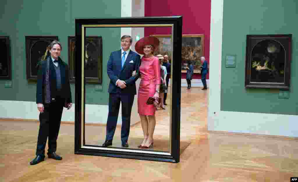 Queen Maxima (R) and King Willem-Alexander of the Netherlands (C) pose in a giant picture frame as they tour the "Hollaender-Saal" (Dutchmen Hall) of the Alte Pinakothek museum in Munich, southern Germany.