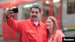 ທ່ານນິໂຄລາ ມາດູໂຣ (Nicolas Maduro) ປະທານາທິບໍດີ ຂອງເວເນຊູເອລາ ຢືນຖ່າຍຮູບແບບແຊລຟີ ກັບພັນລະຍາຂອງທ່ານ, ທ່ານນາງ ຊີເລຍ ຟລໍເຣສ (Cilia Flores) ໃນຂະນະທີ່ພວກເຂົາເຈົ້າ ໄປເຖິງບ່ອນ ທີ່ຈະປະຊຸມກັນ ກັບພວກພະນັກງານ ໃນຂະແໜງຂົນສົ່ງ ໃນນະຄອນ Caracas ໃນວັນທີ 24 ມັງກອນ, 2018.