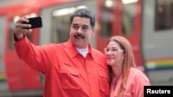Venezuela's President Nicolas Maduro takes a selfie next to his wife, Cilia Flores, as they arrive for a rally with workers of transport sector in Caracas, Venezuela, Jan. 24, 2018.