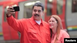 Venezuela's President Nicolas Maduro takes a selfie next to his wife, Cilia Flores, as they arrive for a rally with workers of transport sector in Caracas, Venezuela, Jan. 24, 2018.