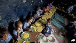 Children eat a meal at a school in a shanty neighborhood of New Delhi, India, Sept. 13, 2012.