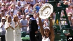 Serena Williams of the United States reacts as she holds up the trophy after winning the women's singles final against Garbine Muguruza of Spain, at the All England Lawn Tennis Championships in Wimbledon, London, July 11, 2015. 