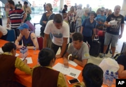 Passengers talk to airline workers as their flights are cancelled at Ngurah Rai International Airport in Denpasar, Bali, Indonesia, Nov. 28, 2017.