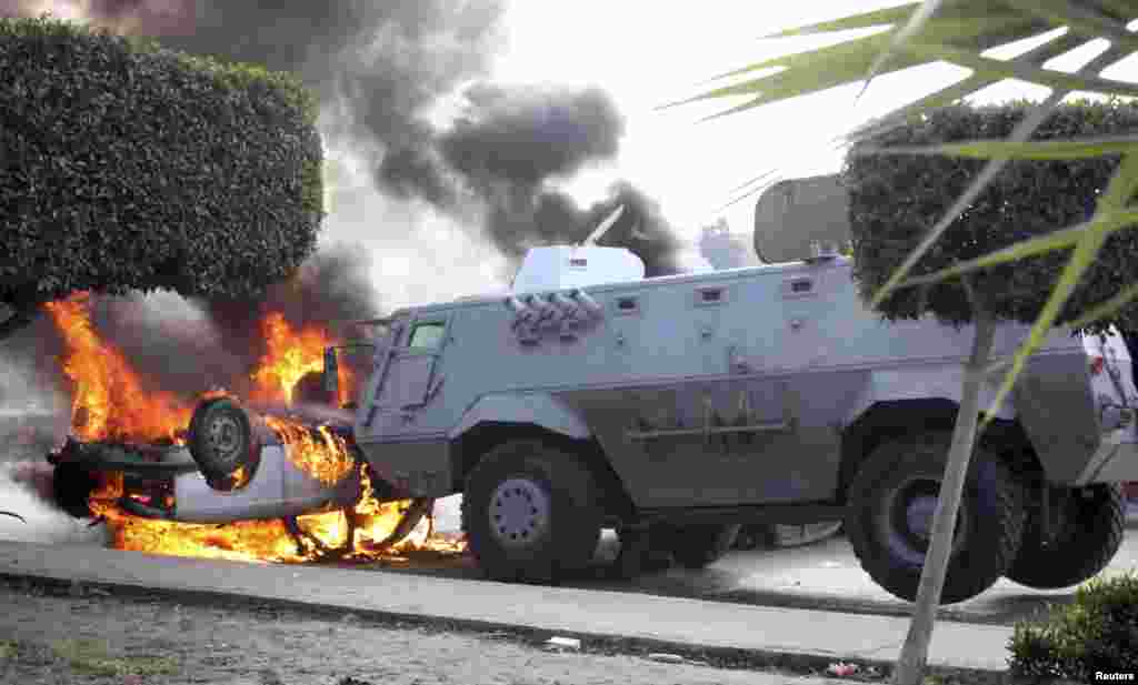 Protesters set a car on fire near a police vehicle during clashes with riot police at Nasr City district in Cairo, Eghpt.