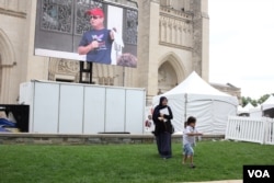 A young family plays alongside the main stage at the start of the One Journey Festival in support of refugees at Washington's National Cathedral, Washington, June 2, 2018, (V. Macchi/VOA)