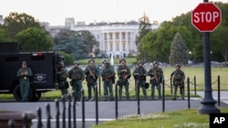 Law enforcement officers from Calvert County Maryland Sheriff's Office standing on the Ellipse, area just south of the White House in Washington, as they watch demonstrators protest the death of George Floyd, Sunday, May 31, 2020. 